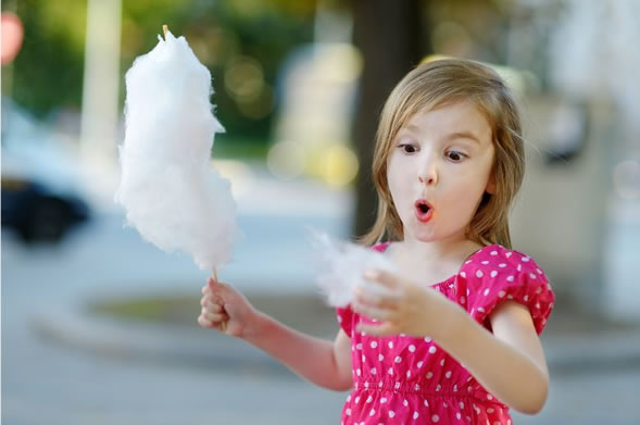 Girl in pink dress holding cotton candy.