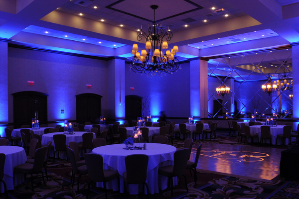 A beautifully lit event space with blue lighting and round tables.