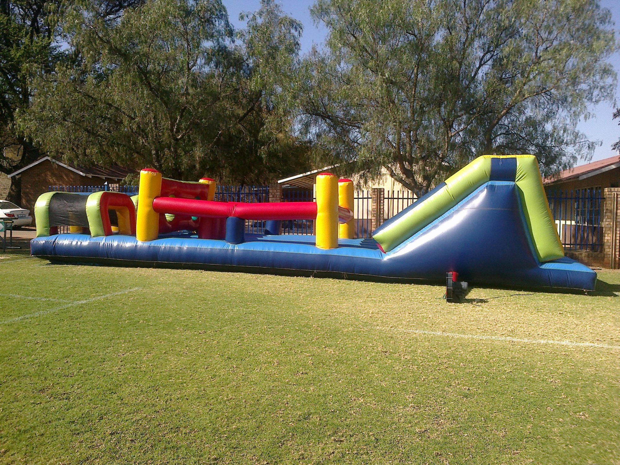 Inflatable water castle with slides and obstacles in a grassy area