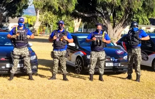 Four security personnel in uniform standing with vehicles.