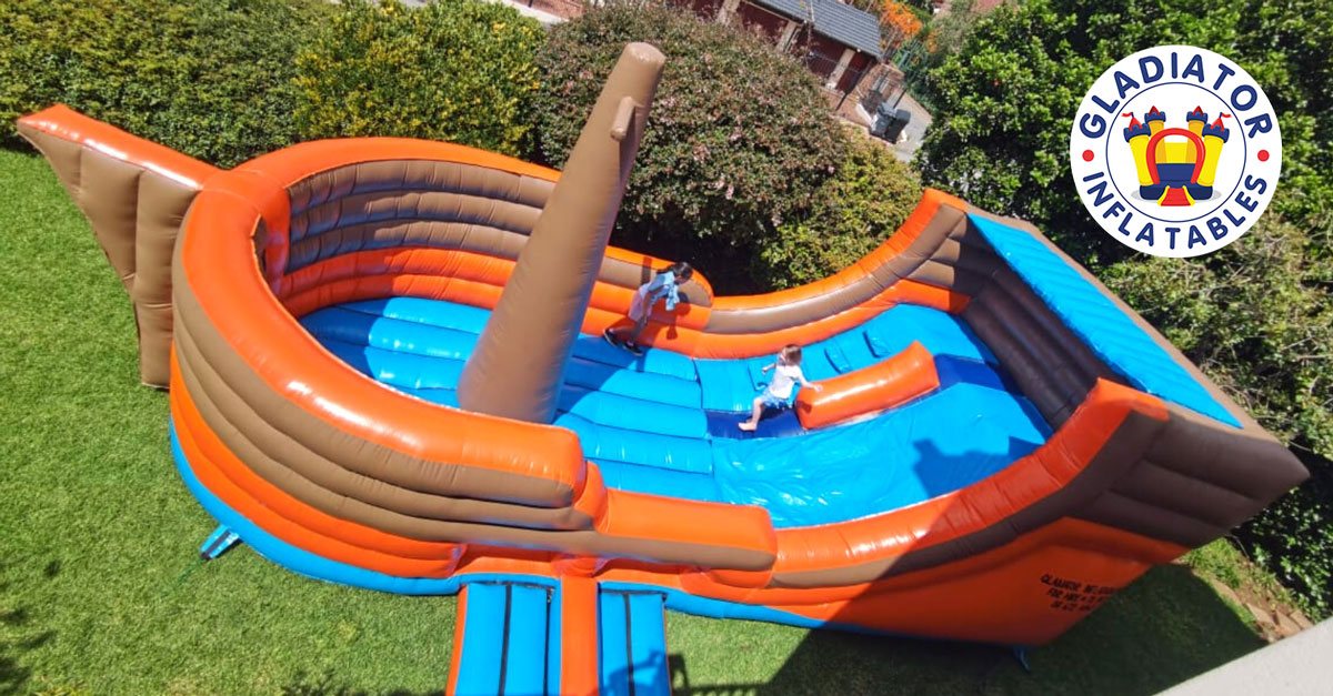 Pirate-themed jumping castle with orange and blue design in a garden