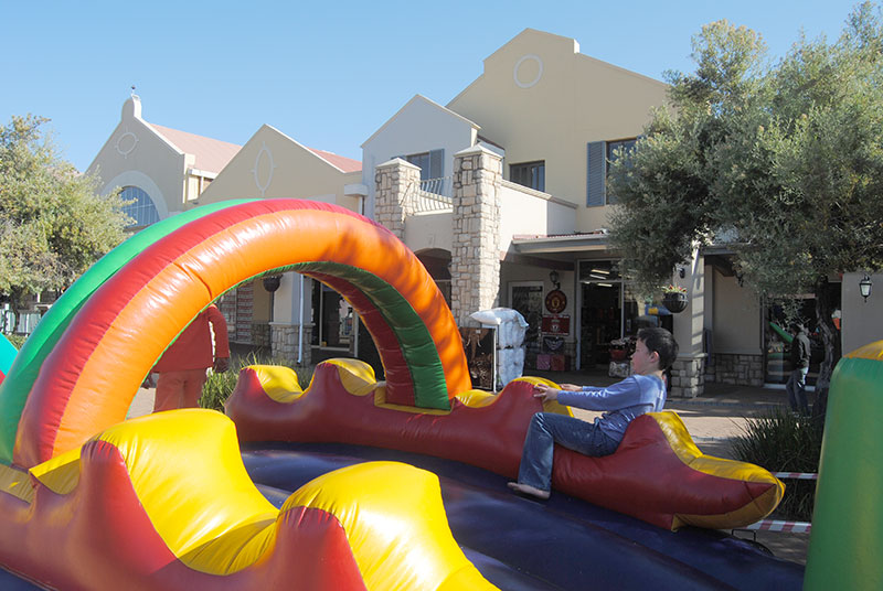 Colorful inflatable slide with rainbow arch in an outdoor setting.