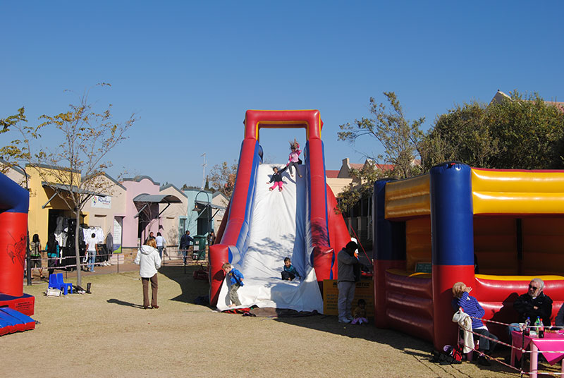 Inflatable water slide with children playing at the base.
