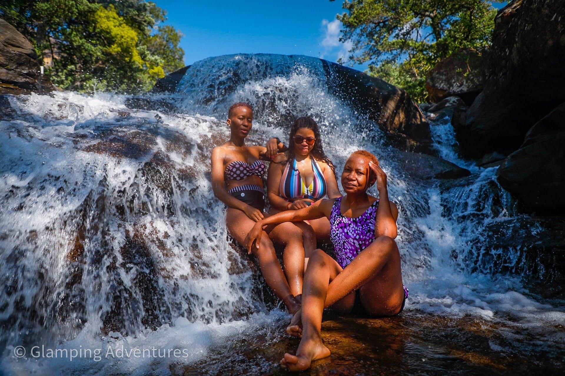 Guests enjoying a waterfall at a glamping retreat in nature