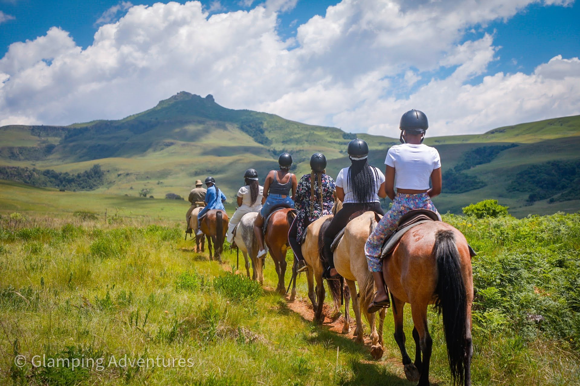Group of people riding horses through a scenic landscape.