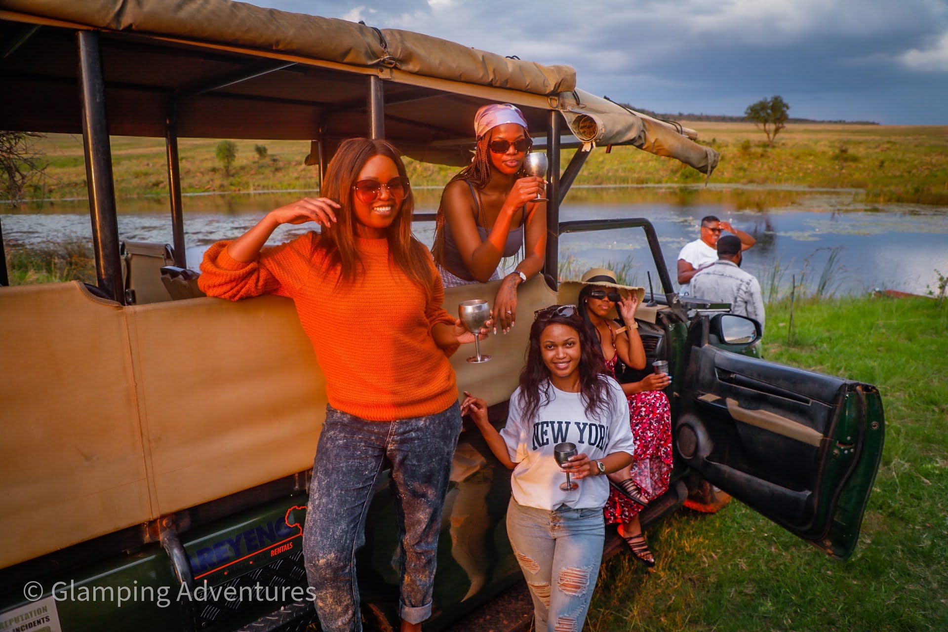 Group of friends enjoying a safari glamping experience by a lake