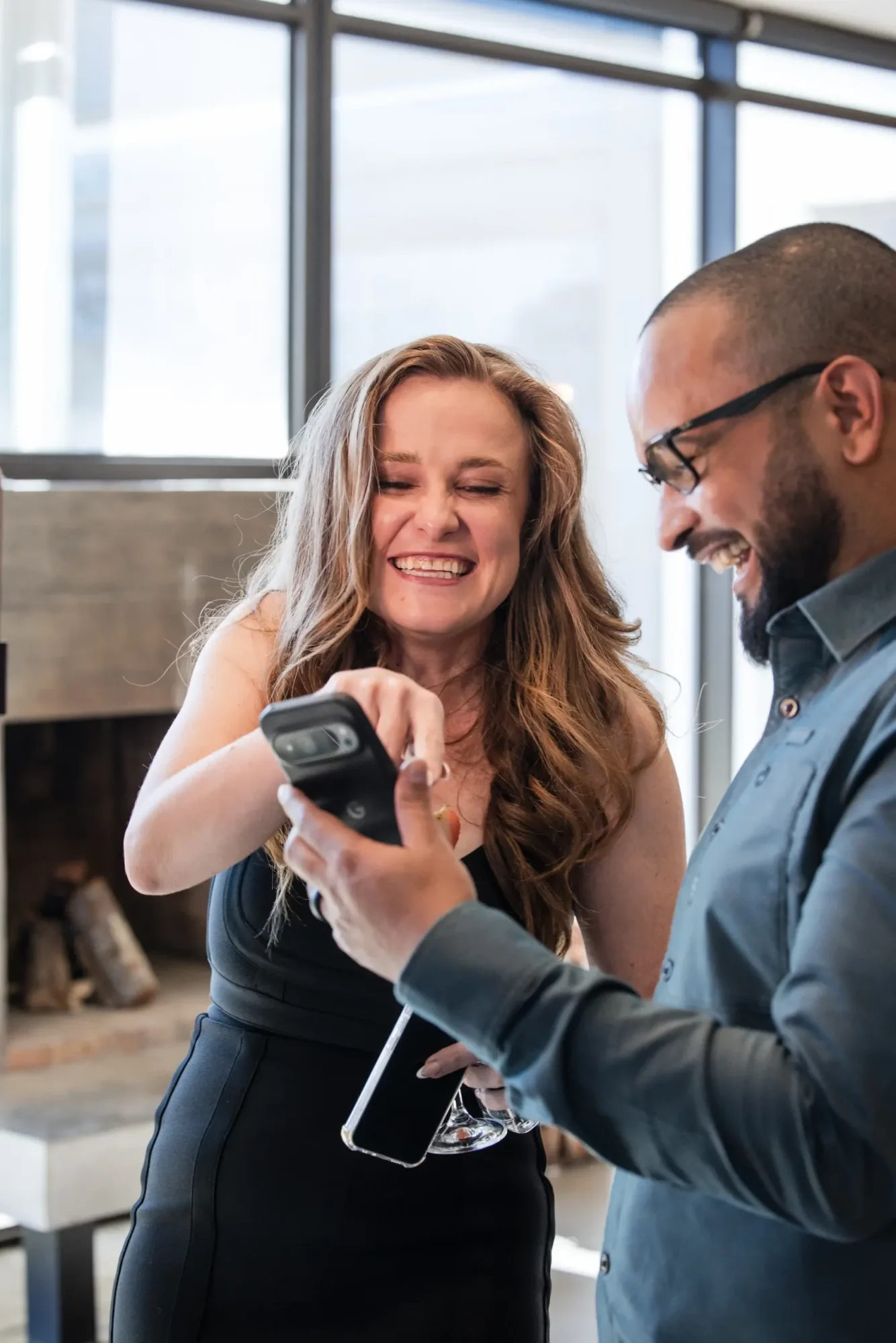 Two smiling guests looking at a smartphone together.