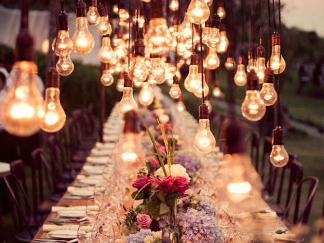 Outdoor dining table with hanging lights and flowers