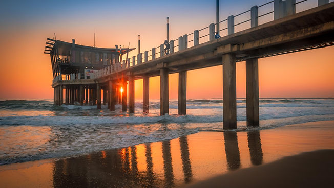 Waterfront venue with pier and sunset reflections.