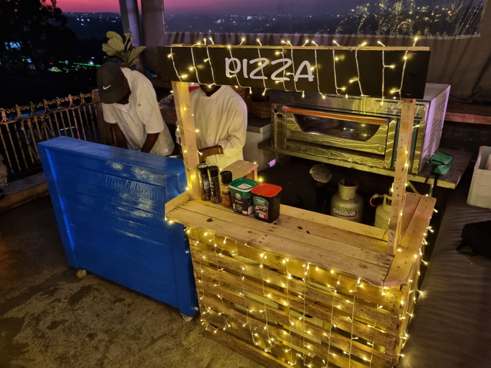 Pizza cart with toppings and staff preparing pizza