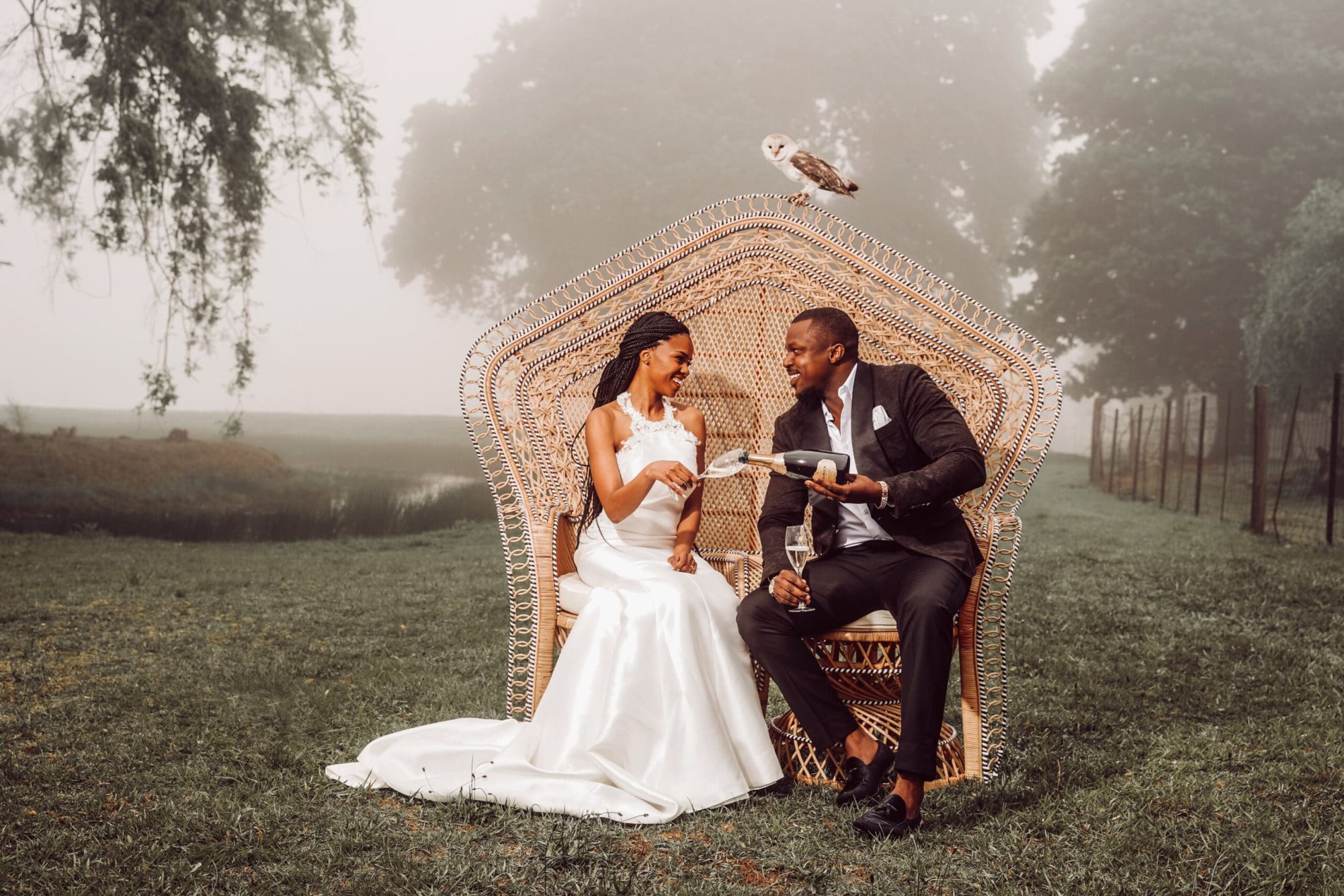 Couple seated on a Peacock Pose Emperor Chair in a misty outdoor area.