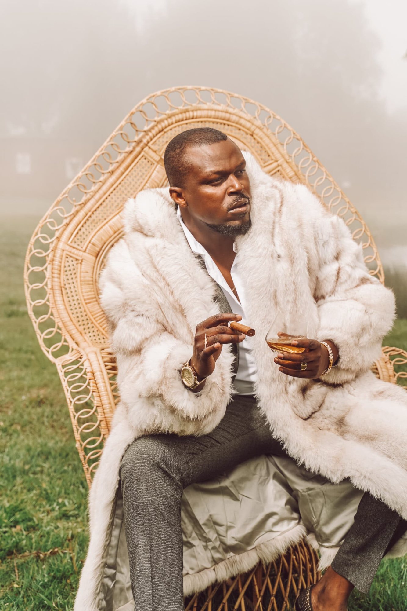 Man sitting elegantly on a peacock throne chair outdoors.
