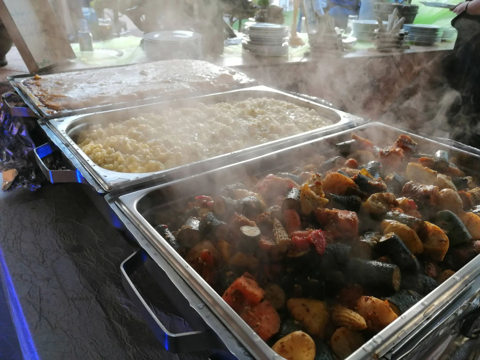 Steaming food trays with mixed vegetables and pasta