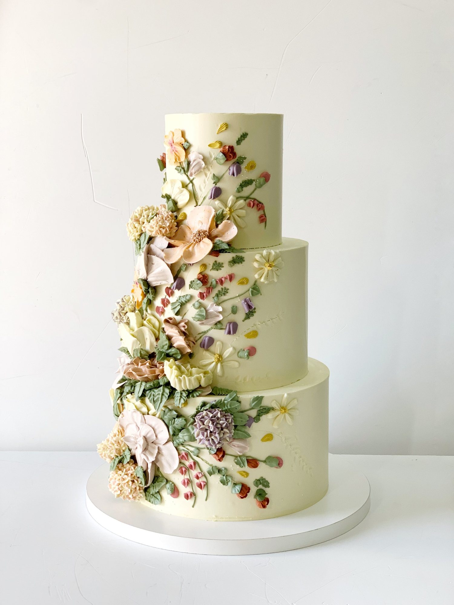 A three-tier cake with floral decorations on a white base.
