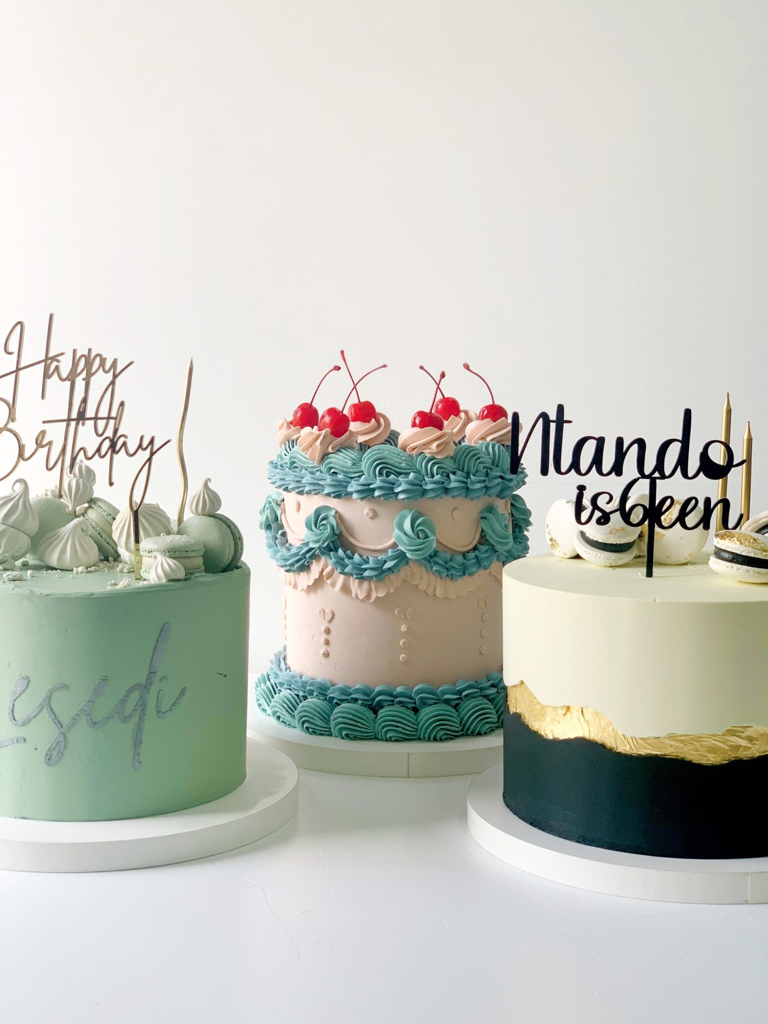 Three decorated birthday cakes with colorful icing and toppers.