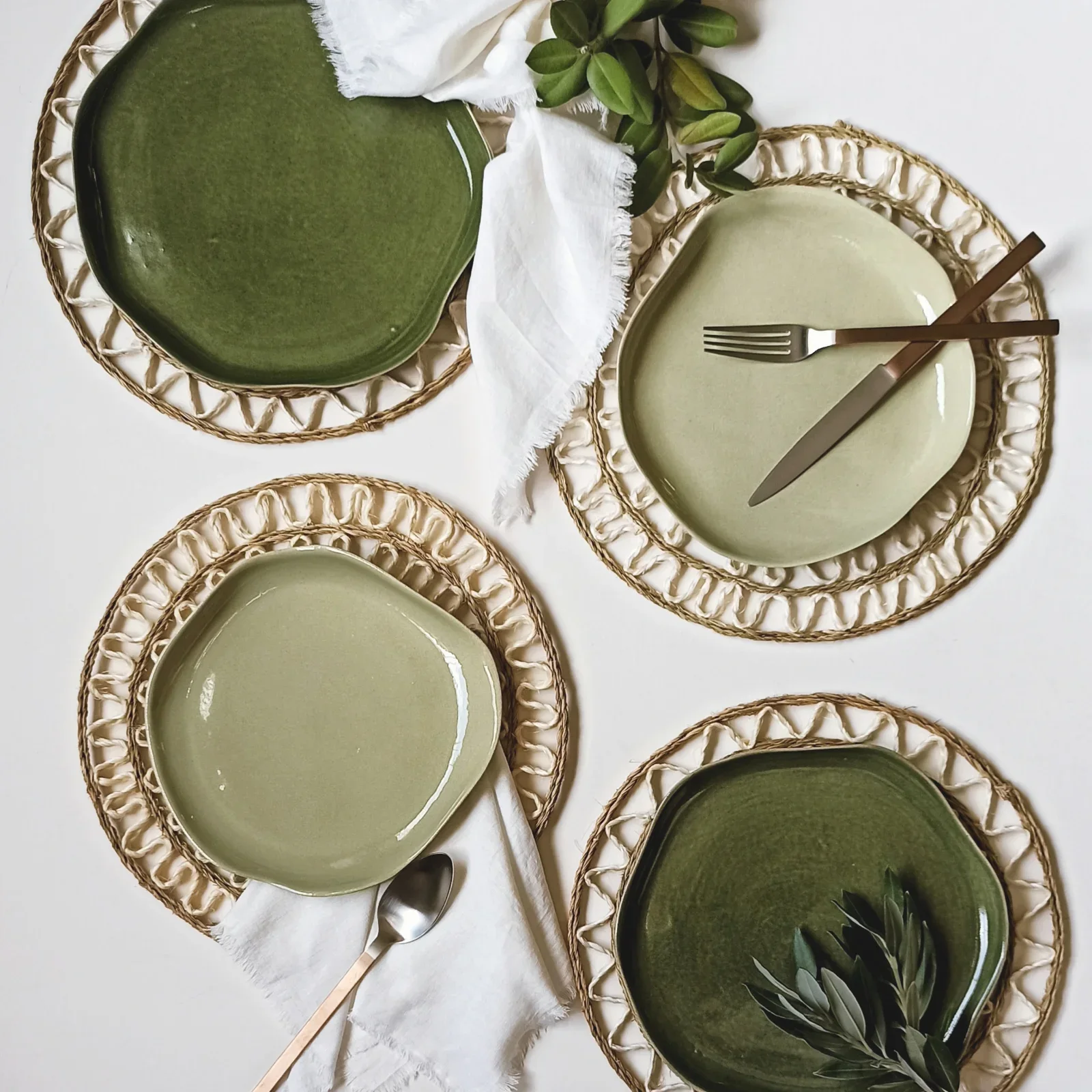 Four green ceramic plates on textured woven placemats