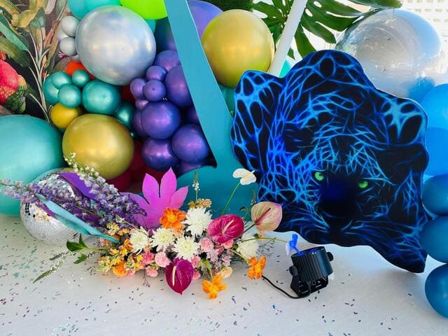 Colorful balloons and flowers arranged for an event backdrop.