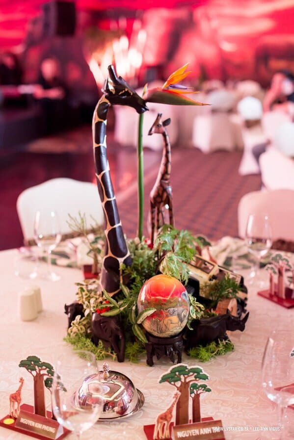 Table centerpiece with wooden giraffes and a bird of paradise flower.