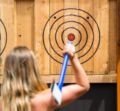 Person preparing to throw an axe at a wooden target.