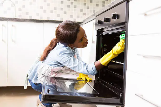 Woman cleaning an oven in a modern kitchen