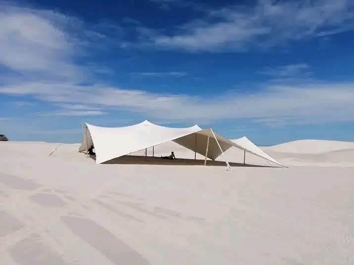 White stretch tent set up on a sandy landscape