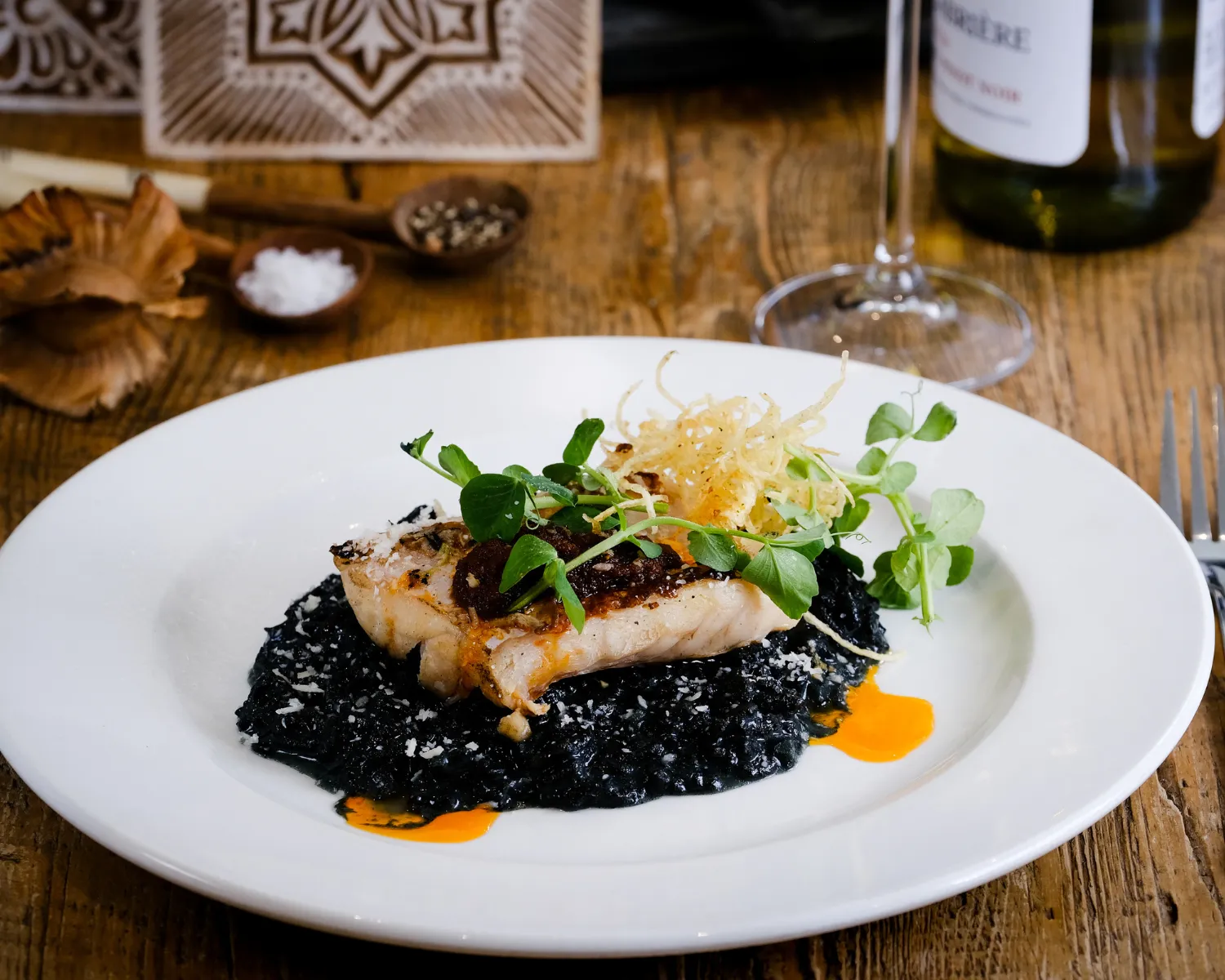 Grilled fish on black rice with microgreens and sauce