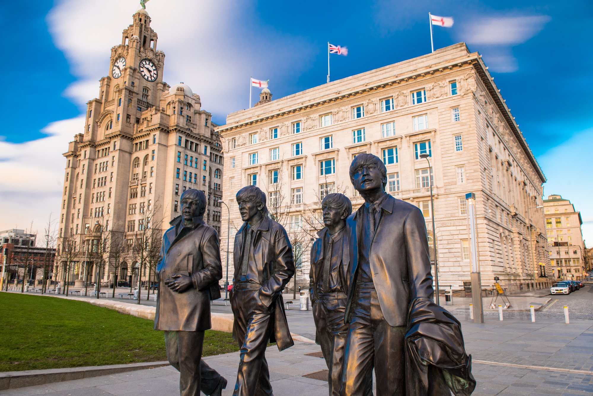 Four bronze statues walking in front of a historic building