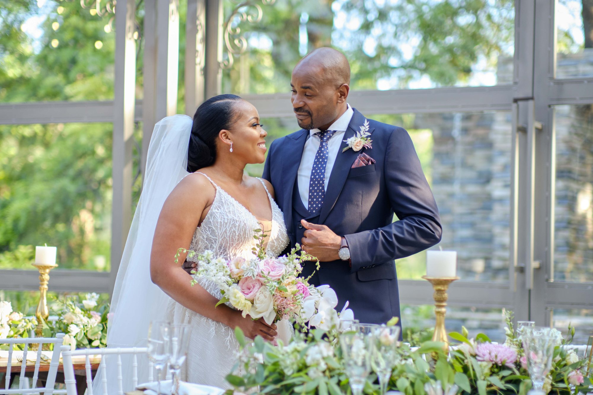 Couple in wedding attire surrounded by flowers and candles