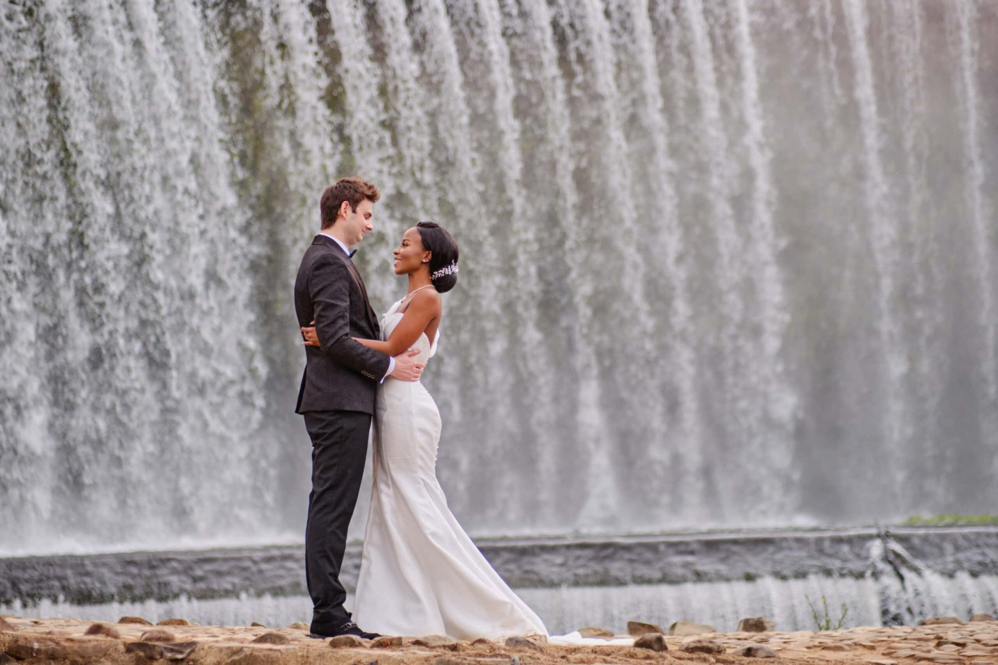 Couple embracing in front of a waterfall