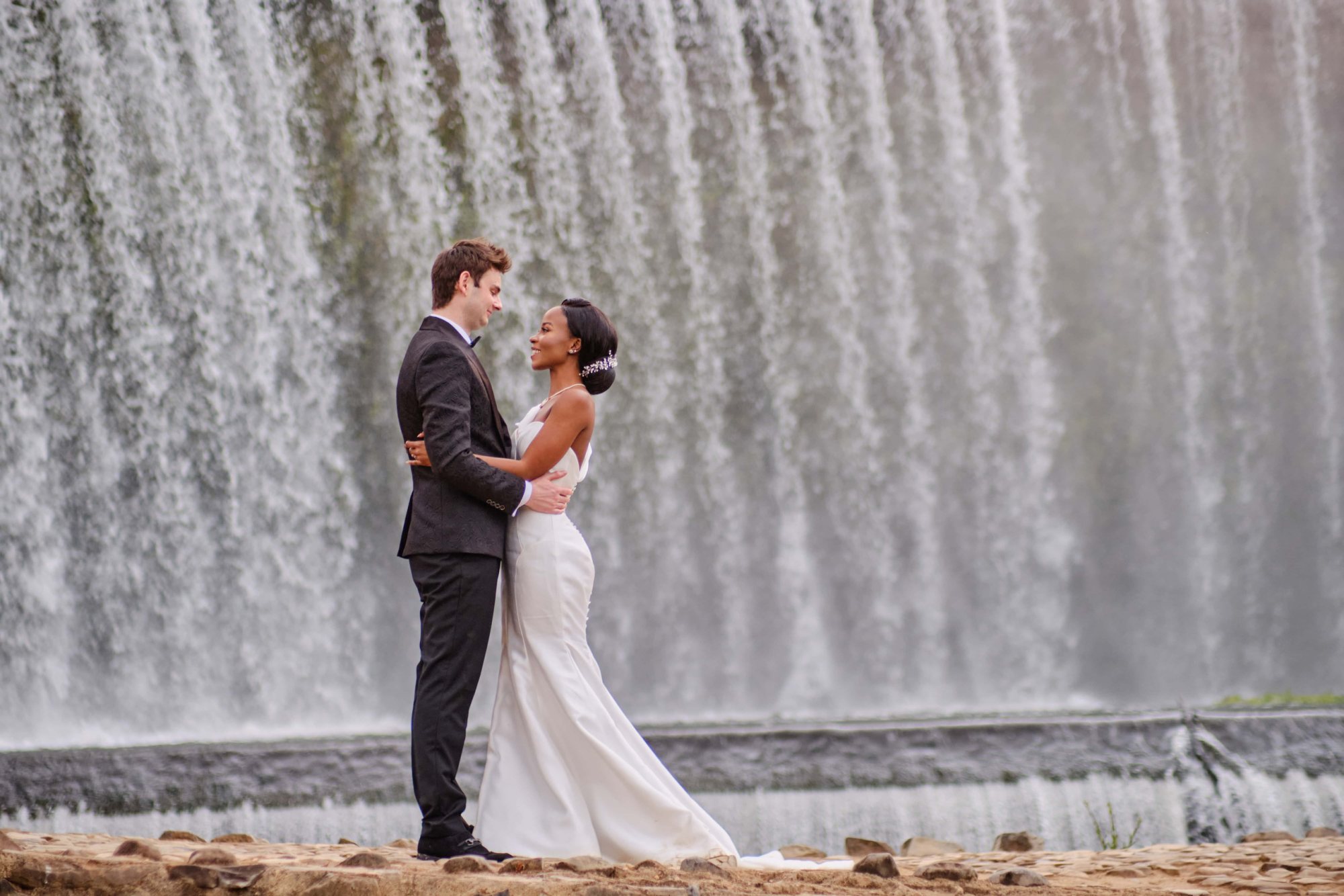 Couple embracing in front of a waterfall