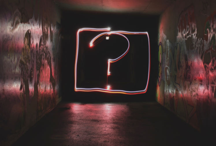Light art in a dark corridor forming a question mark