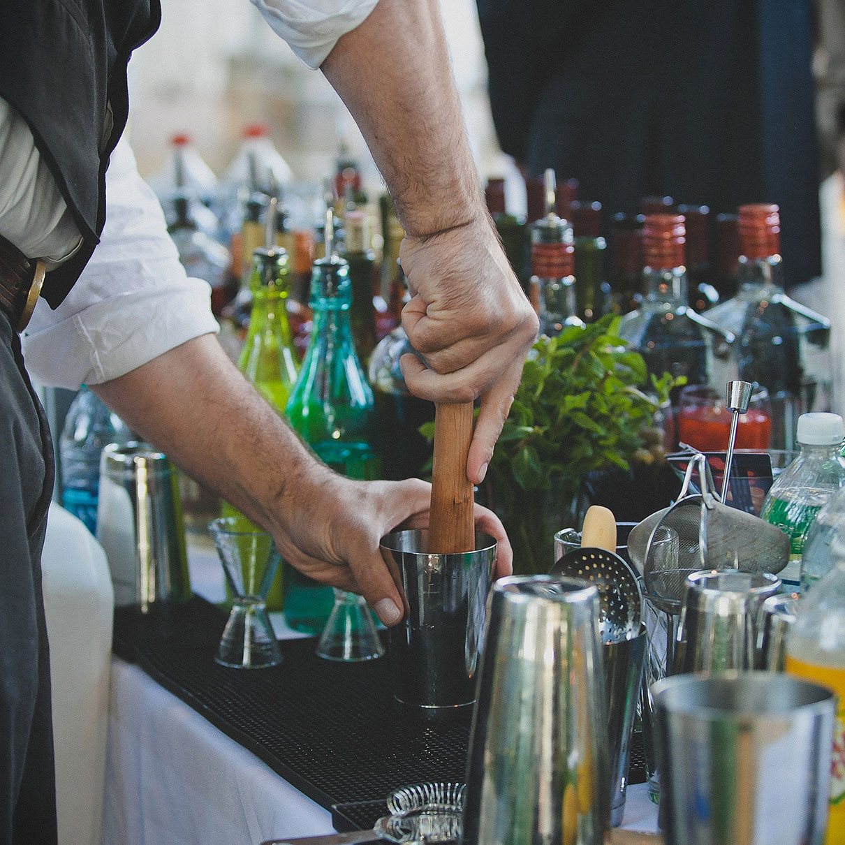 Bartender mixing cocktails with fresh ingredients and tools.