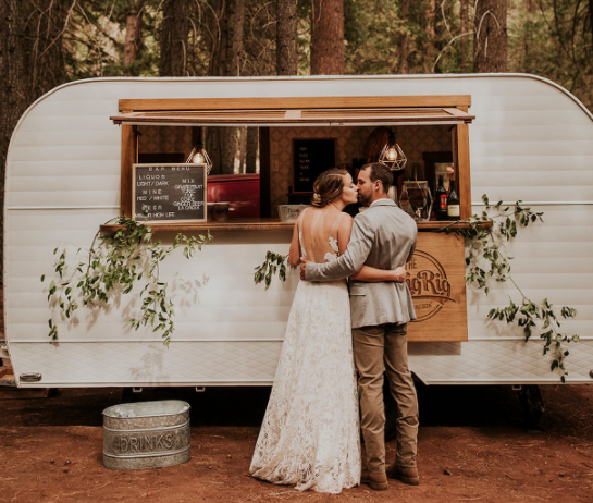 Outdoor mobile bar trailer with a couple by it.