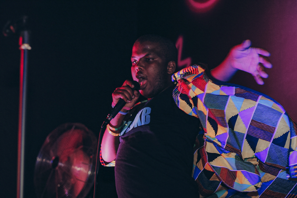 A performer singing passionately on stage with a mic