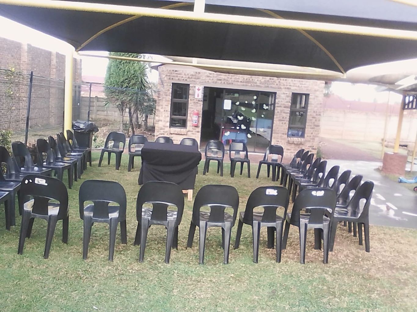 Circular arrangement of black chairs on grass under shade
