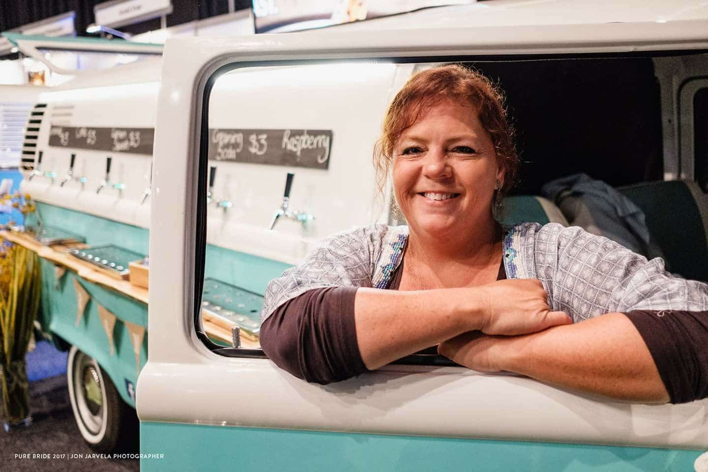 A woman smiling next to the Kombi Keg mobile bar