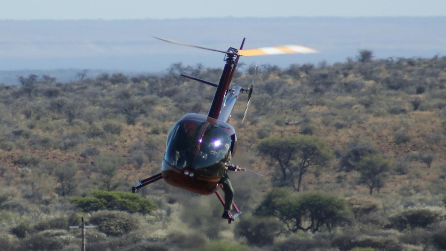 Helicopter performing a dynamic maneuver over a scenic landscape.
