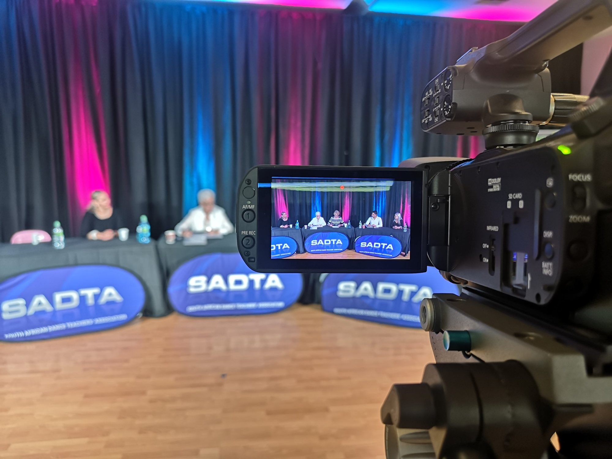 Camera focusing on a panel discussion with SADTA branding