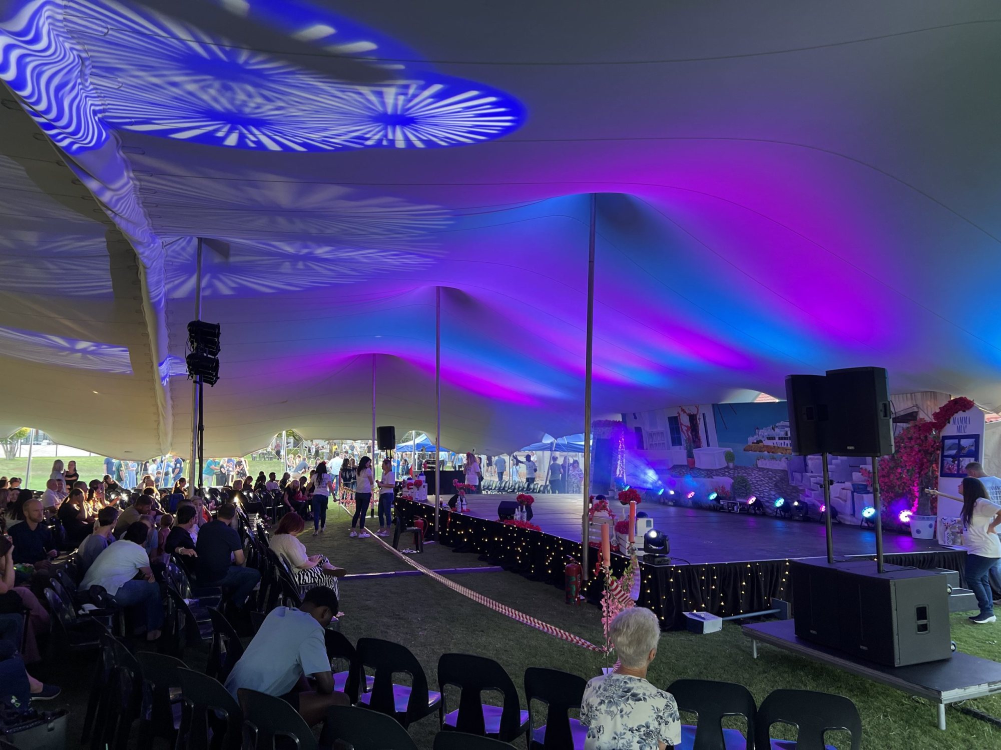 Event tent interior setup with colorful lighting effects.