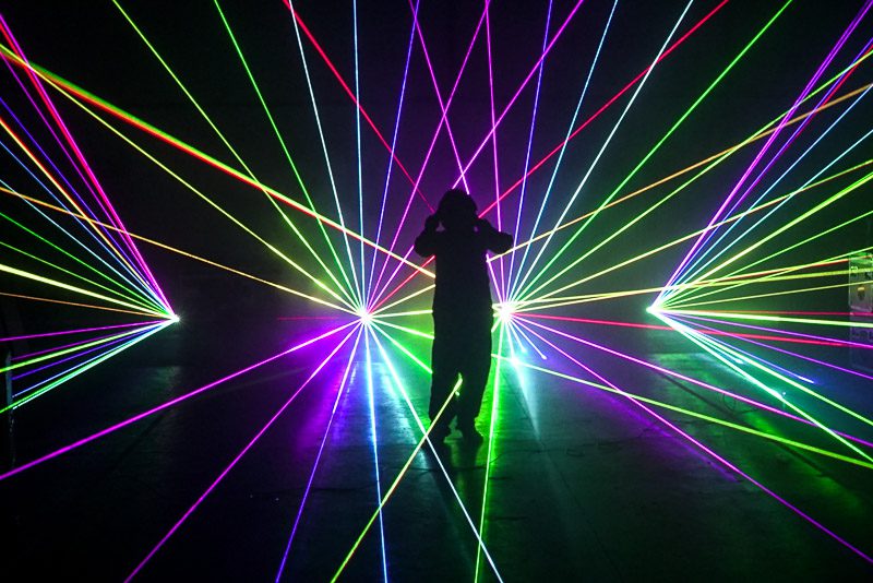 Colorful laser beams in a dark setting with a silhouette