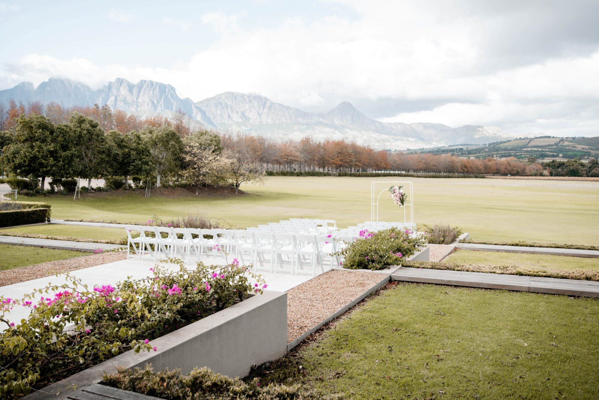 White chairs set up for a wedding ceremony with mountains in the distance.