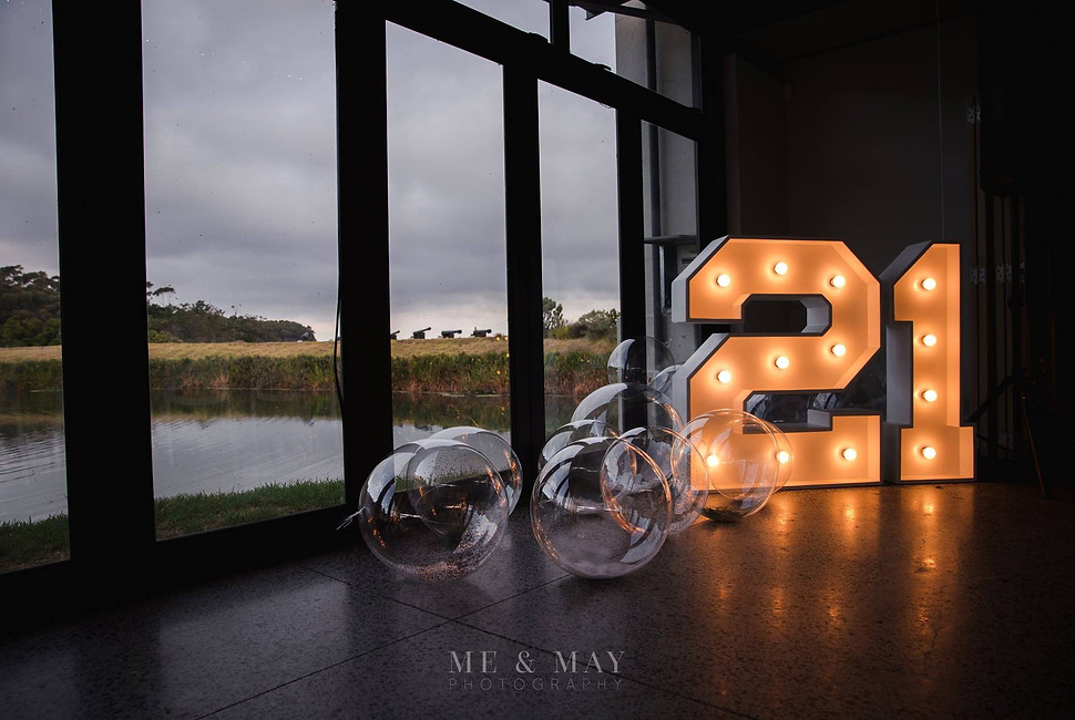 Illuminated 21 marquee lights with bubbles near a window.