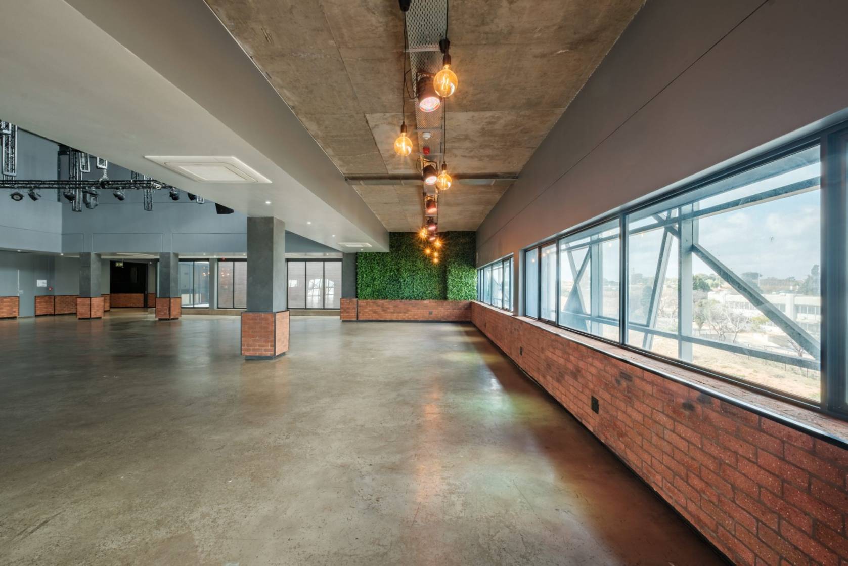 Interior view of a spacious event venue with large windows and industrial decor