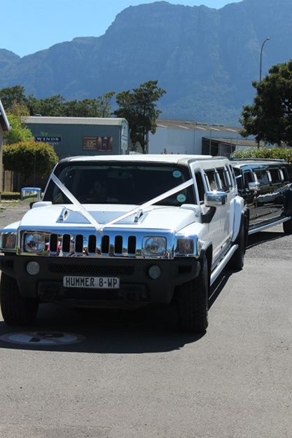 Two white stretched Hummer limousines parked on the street