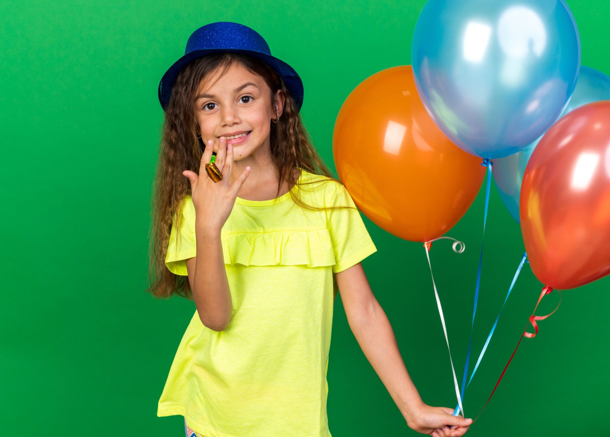 Girl in yellow top holding balloons with a smile