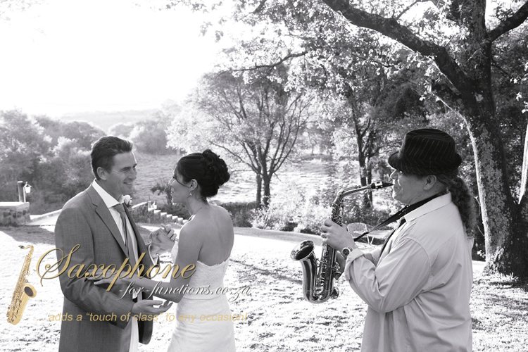 Saxophonist performs for a couple at a wedding.