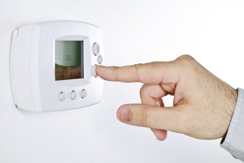 Hand adjusting a thermostat control panel.