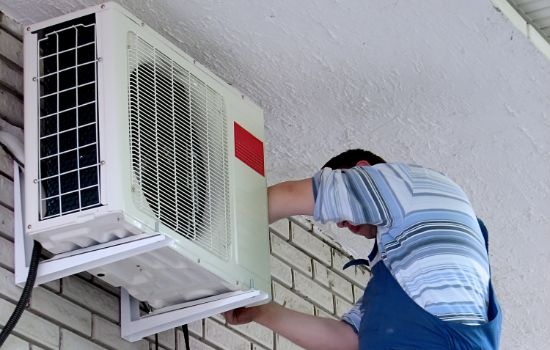Technician installing air conditioning unit on a wall
