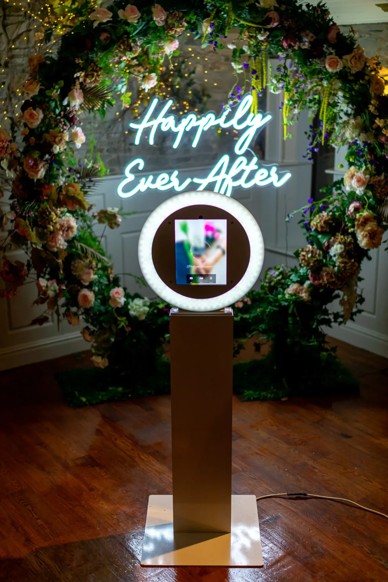 Floral photo booth with 'Happily Ever After' neon sign.