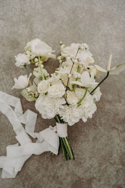 Stylish white floral bouquet with ribbon on a textured surface